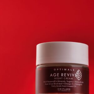 Elegant night cream jar on a striking red background, perfect for skincare promotions.