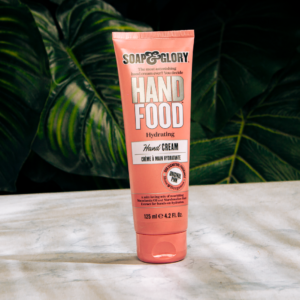 Soap & Glory Hand Food cream tube on marble surface with leaf background.