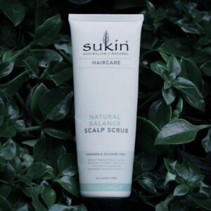 a tube of sukin natural scalp scrub sitting in a bush