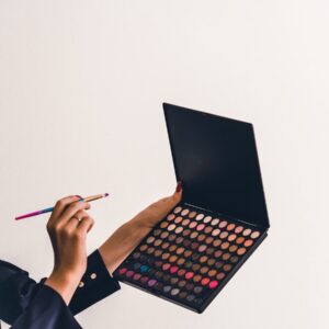 a person holding a makeup palette and a pencil